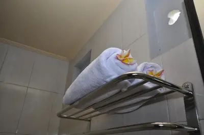 a towel rack with towels on it in a bathroom at Putu Guest House 2 in Canggu