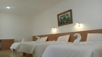 a group of three beds with white sheets and swans on them at Guest House Simalem in Legian