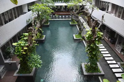 an indoor pool in a building with trees in it at Ramada by Wyndham Bali Sunset Road Kuta in Kuta