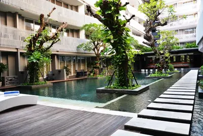 a swimming pool with trees in the middle of a building at Ramada by Wyndham Bali Sunset Road Kuta in Kuta
