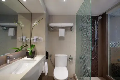 a bathroom with a toilet and a sink and a shower at Ramada by Wyndham Bali Sunset Road Kuta in Kuta