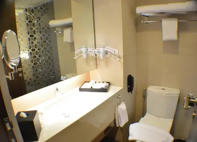 a bathroom with a sink and a toilet and a mirror at Ramada by Wyndham Bali Sunset Road Kuta in Kuta