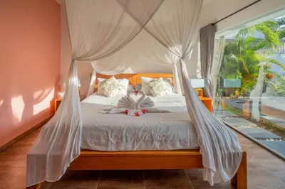 a bedroom with a canopy bed with a teddy bear on it at La Fortuna in Seminyak