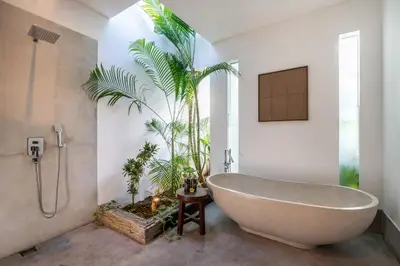 a bathroom with a bath tub and a palm tree at Villa WoW Canggu in Canggu