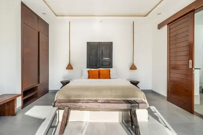 a bedroom with a bed and a wooden door at Villa WoW Canggu in Canggu