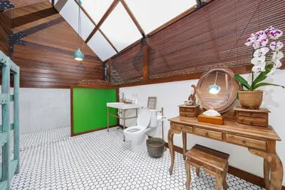 a bathroom with a toilet and a table and a sink at Atra Bambulogy Villa by Bambulogy Resort in Kerobokan
