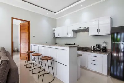 a kitchen with white cabinets and bar stools at Villa Voyage 4 in Seminyak