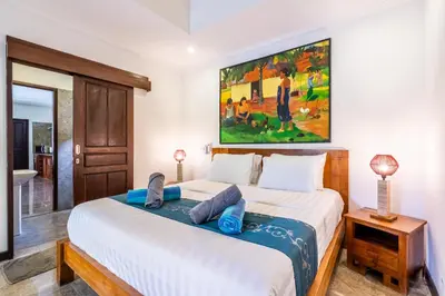 a bedroom with a bed with a large painting on the wall at Madu Villa Seminyak in Seminyak