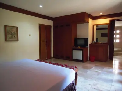 a bedroom with a bed and a television in it at Ananda Resort Seminyak in Seminyak