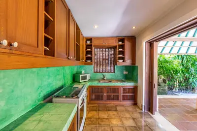 a kitchen with wooden cabinets and green counter tops at Villa Angsa by Nakula in Sanur
