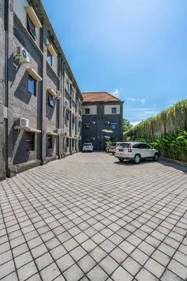 a parking lot with cars parked in front of a building at Ganandra Stay Denpasar in Denpasar