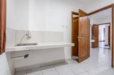 a kitchen with a sink and a wooden door at Ganandra Stay Denpasar in Denpasar