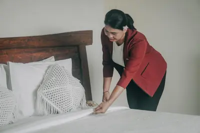 a woman making a bed in a bedroom at Amalia Swan Haven Villa Seminyak in Seminyak