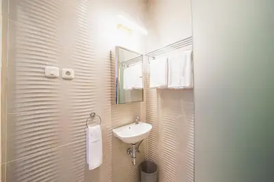 a white bathroom with a sink and a mirror at Umaja Villa in Seminyak