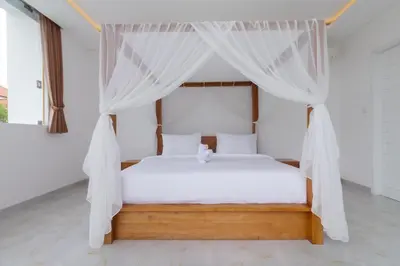 a bedroom with a white bed with a canopy at Villa Kusamakura Seminyak in Seminyak