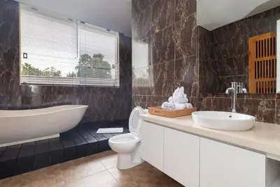 a bathroom with a tub and a toilet and a sink at Villa Kusamakura Seminyak in Seminyak