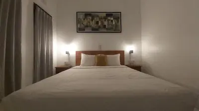 a bedroom with a white bed with two lamps at Genta House in Kuta