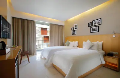 a hotel room with a large bed and a television at Ossotel Legian in Legian