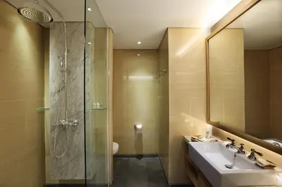 a bathroom with a shower and a sink and a mirror at Ossotel Legian in Legian