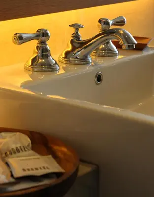a bathroom sink with a chrome faucet on it at Ossotel Legian in Legian