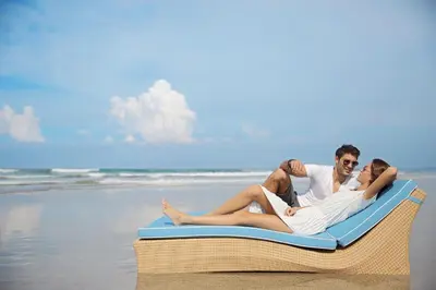 three people laying on aogie board on the beach at Ossotel Legian in Legian