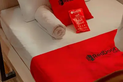 a bed with red and white towels on it at RedDoorz Hostel Near Ngurah Rai Airport Kuta in Kuta