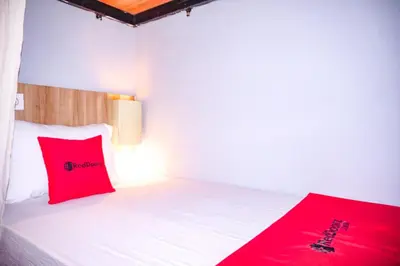 a bedroom with a bed with red pillows on it at RedDoorz Hostel Near Ngurah Rai Airport Kuta in Kuta