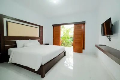 a bedroom with a bed and a flat screen tv at Kadek Bagus Guesthouse Denpasar Mitra RedDoorz in Kerobokan