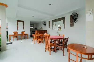 a dining room with wooden tables and chairs at Kadek Bagus Guesthouse Denpasar Mitra RedDoorz in Kerobokan