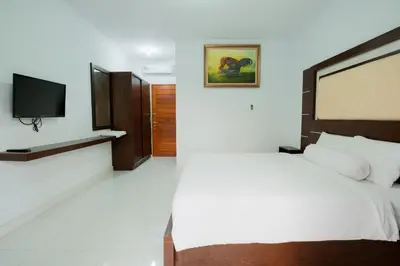 a bedroom with a bed and a flat screen tv at Kadek Bagus Guesthouse Denpasar Mitra RedDoorz in Kerobokan