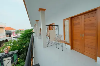 a balcony with a wooden door and chairs on it at Kadek Bagus Guesthouse Denpasar Mitra RedDoorz in Kerobokan