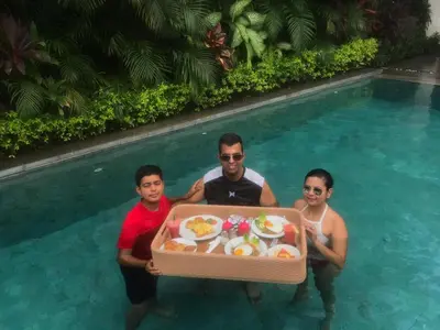 a group of people holding a tray of food in a swimming pool at Serene Villas in Seminyak