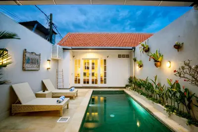 a villa with a swimming pool in front of a house at Casa Su Seminyak in Seminyak
