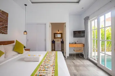 a bedroom with a large white bed and a desk at Casa Nisa Seminyak in Seminyak