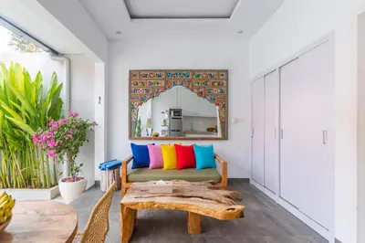a living room with a bench with colorful pillows at Casa Nisa Seminyak in Seminyak