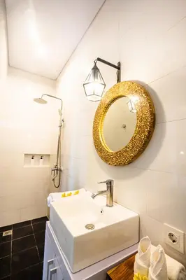 a bathroom with a white sink and a gold mirror at Casa Ku Seminyak in Seminyak