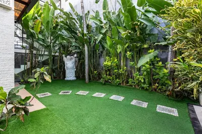 a garden with a green floor and a statue at Saga Villas Legacy in Seminyak