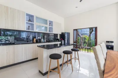a kitchen with a bar with stools and a table at Saga Villas Legacy in Seminyak