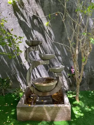 a fountain with a bowl and stairs in a garden at Saga Villas Legacy in Seminyak