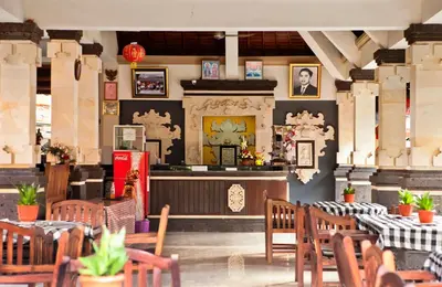 a restaurant with tables and chairs and a bar at Troppo Zone Puri Rama Resort Kuta in Legian