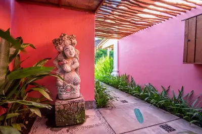 a statue in front of a pink wall with plants at PinkPrivate Sanur - for Cool Adults Only in Sanur