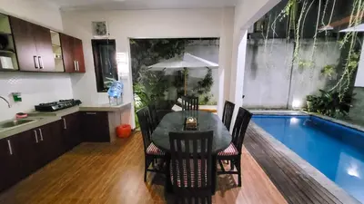 a kitchen and dining room with a table and a swimming pool at Ramantika Sunset Bay in Nusa Dua