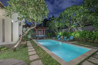 a swimming pool in a yard with chairs and trees at Leluhur 1 Private Pool Villa in Seminyak
