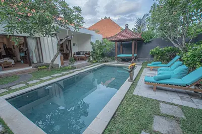 a swimming pool with lounge chairs and a house at Leluhur 1 Private Pool Villa in Seminyak