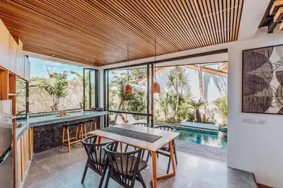 a dining room with a table and chairs and a pool at Beyond Bespoke Villas in Seminyak