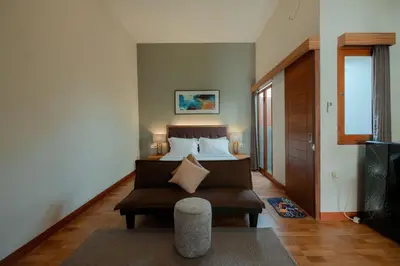 a bedroom with a bed and a chair and a couch at Andewi Guest House Denpasar RedPartner - Minimum Stay 30 Nights in Sanur