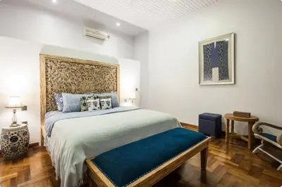 a bedroom with a king sized bed with a blue seat at Villa Alexandra Seminyak By Island Escape in Seminyak