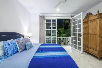 a bedroom with a blue bed and a balcony at Villa Alexandra Seminyak By Island Escape in Seminyak