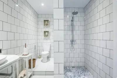 a white tiled bathroom with a shower and a toilet at Villa Alexandra Seminyak By Island Escape in Seminyak