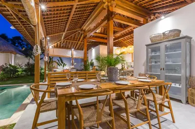 a dining room with a table and chairs and a pool at Villa KIU by Alfred in Bali in Seminyak